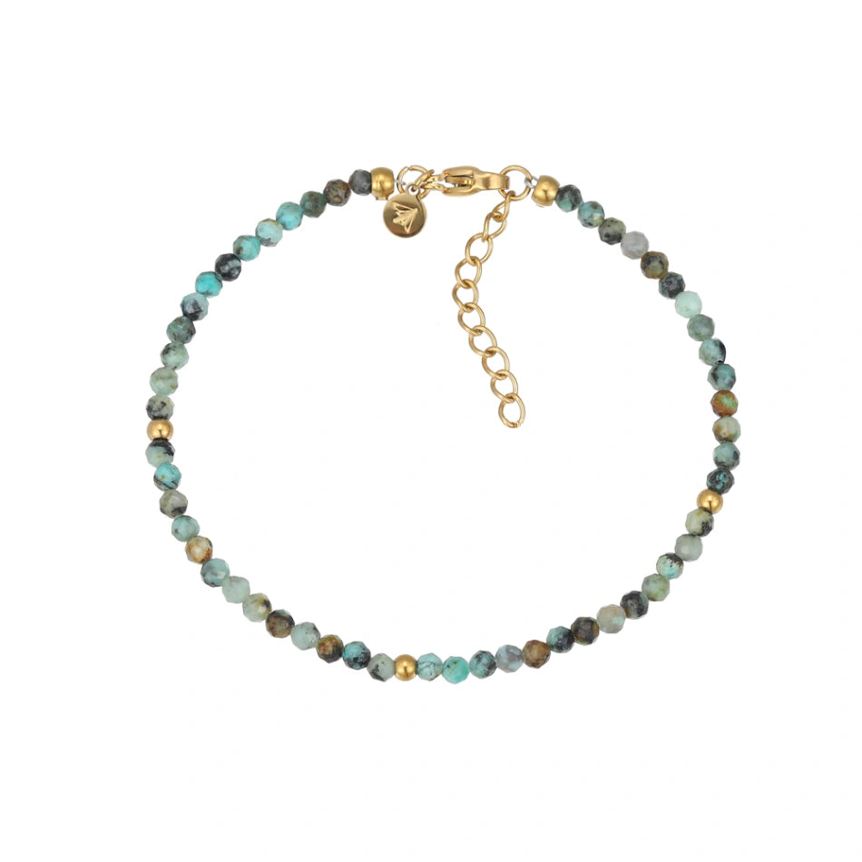 Nahaufnahme eines eleganten Armbands aus facettierten afrikanischen Türkisperlen mit goldenen Akzenten und einem verstellbaren goldfarbenen Karabinerverschluss auf weißem Hintergrund. Perfekt für stilvolle Damen.