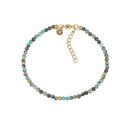 Nahaufnahme eines eleganten Armbands aus facettierten afrikanischen Türkisperlen mit goldenen Akzenten und einem verstellbaren goldfarbenen Karabinerverschluss auf weißem Hintergrund. Perfekt für stilvolle Damen.