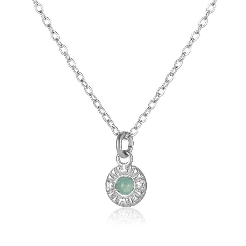 Elegante Silberhalskette mit einem runden Anhänger, der einen hellgrünen Stein im Zentrum trägt. Das polierte Silber des Anhängers zeigt ein filigranes, sonnenförmiges Muster, perfekt für stilvollen Schmuck.