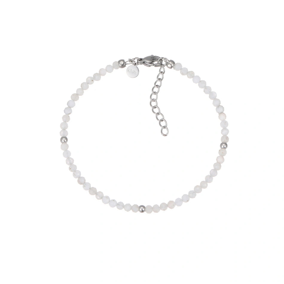 Filigranes Perlenarmband aus schimmernden, facettierten weißen Naturstein-Perlen, akzentuiert mit drei glänzenden Silberkugeln. Es verfügt über einen eleganten silbernen Karabinerverschluss und eine praktische Verlängerungskette, ideal für Damen.